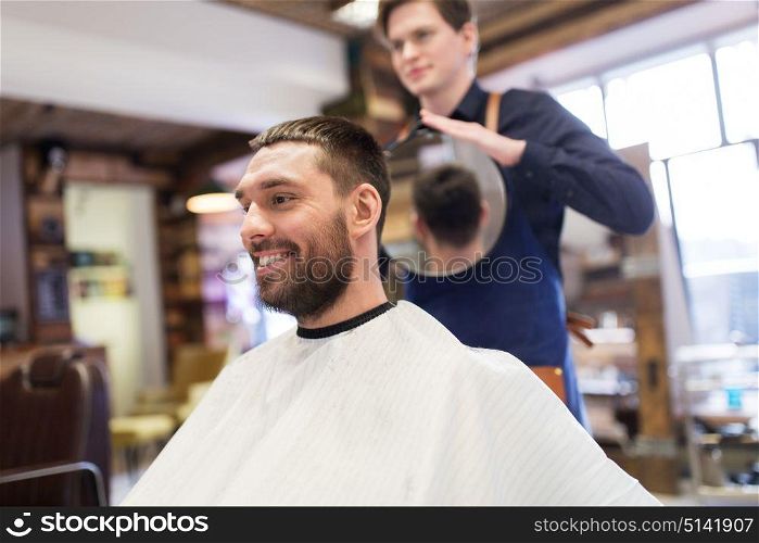 grooming, hairstyle and people concept - man and hairstylist or hairdresser with mirror at barbershop. man and hairdresser with mirror at barbershop