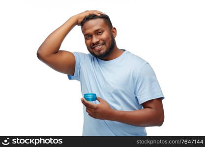 grooming, hairstyling and people concept - smiling young african american man applying hair wax or styling gel over white background. african american man applying hair styling wax