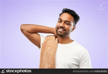 grooming, hygiene and people concept - smiling indian man with bath towel over ultra violet background. indian man with bath towel over violet background