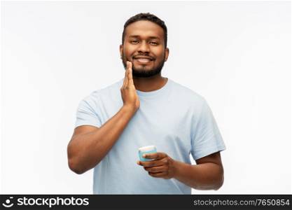 grooming, skin care and people concept - happy african american man applying wax to his beard over white background. happy african man applying wax to his beard