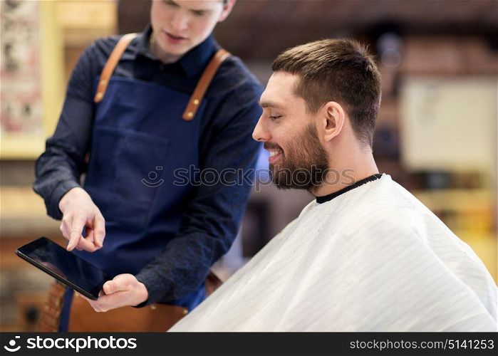 grooming, technology and people concept - hairdresser or barber showing tablet pc computer to man at barbershop. barber showing tablet pc to man at barbershop