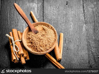 Ground cinnamon in a bowl. On a black wooden table.. Ground cinnamon in a bowl.