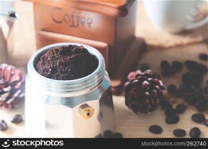 Ground coffee in coffee pot with coffee beans on table, Close up