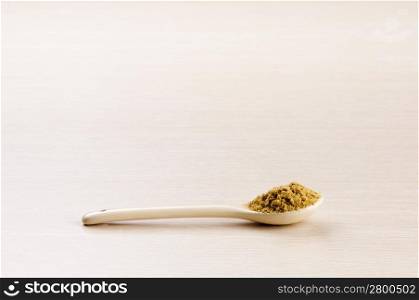 Ground Cumin in a spoon over a blured wooden background with copy space