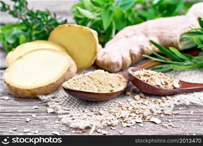 Ground ginger and flakes in two wooden spoons, ginger root on burlap, spicy herbs on a wooden board background