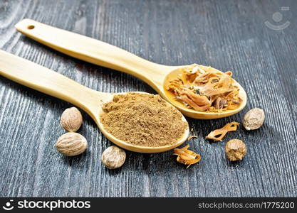 Ground nutmeg and dried nutmeg arillus in two spoons, whole nuts on a wooden board background