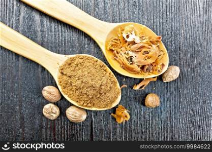 Ground nutmeg and dried nutmeg arillus in two spoons, whole nuts on a wooden board background from above