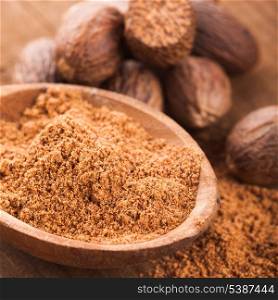 Ground nutmeg spice in the wooden spoon closeup