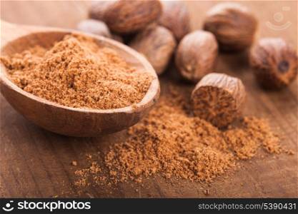 Ground nutmeg spice in the wooden spoon closeup