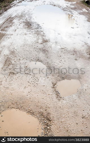 ground road with rainy puddles in spring day