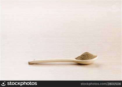 Ground Sage in a spoon over a blured wooden background with copy space