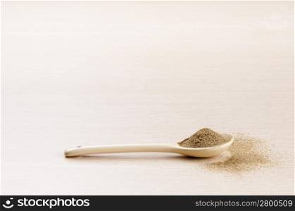 Ground Sage in a spoon with some spilt over the wooden background