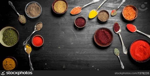 Ground spices in bowls and spoons. On the black chalkboard. Ground spices in bowls and spoons.