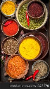 Ground spices in bowls on a wooden tray. On a rustic background.. Ground spices in bowls on a wooden tray.