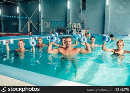 Group aqua aerobics traninig with dumbbells in indoor swimming pool, women class