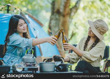 Group beautiful Asian women friends travelers relaxing in c&chairs at tent, They are cheering and drinking beer during c&ing, talking with fun and happy together, copy space