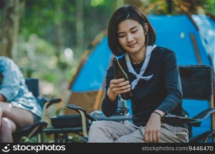 Group beautiful Asian women friends travelers relaxing in camp chairs at tent, They are cheering and drinking beer during camping, talking with fun and happy together, copy space
