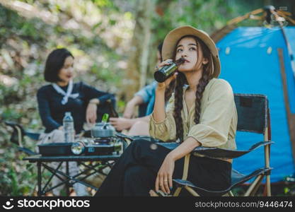 Group beautiful Asian women friends travelers relaxing in camp chairs at tent, They are cheering and drinking beer during camping, talking with fun and happy together, copy space