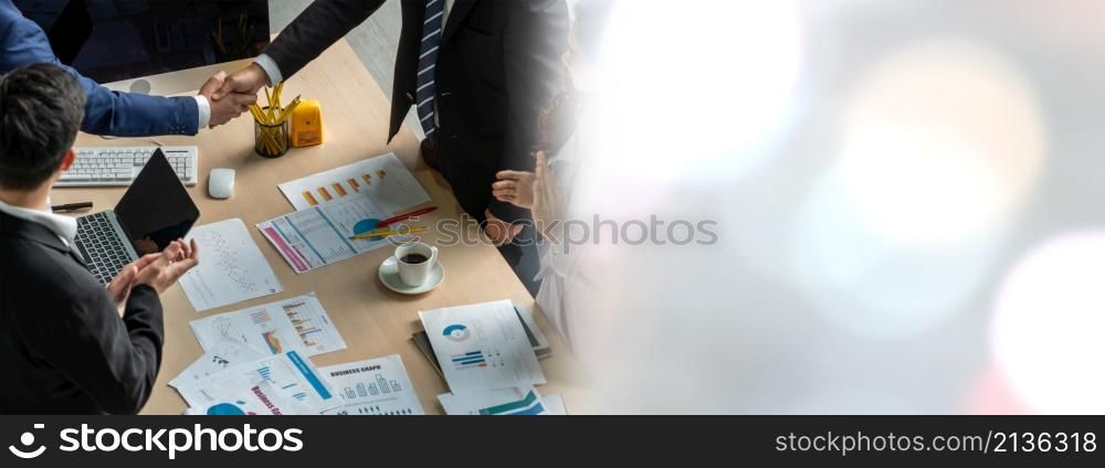 Group business people handshake at meeting table in widen view in office together with confident shot from top view . Young businessman and businesswoman workers express agreement of investment deal.. Group business people handshake at meeting table in widen view