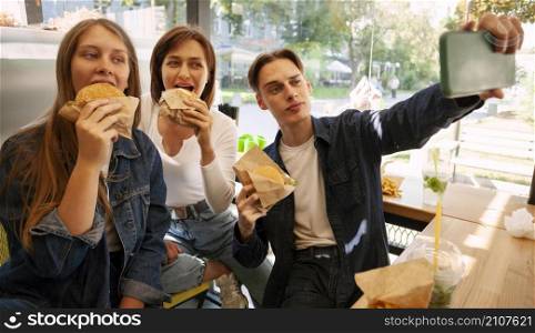 group friends taking selfie while eating fast food