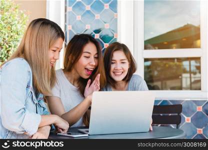 Group happy asian women friends watching media content on line in laptop sitting in coffee shop. Happy asian women friends giving laptop gift to surprised girl in coffee shop. Shopping online concept.