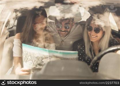 group happy friends looking map sitting inside car