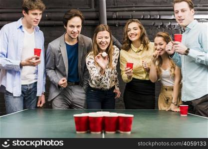 group happy smiling friends enjoying beer pong game table bar