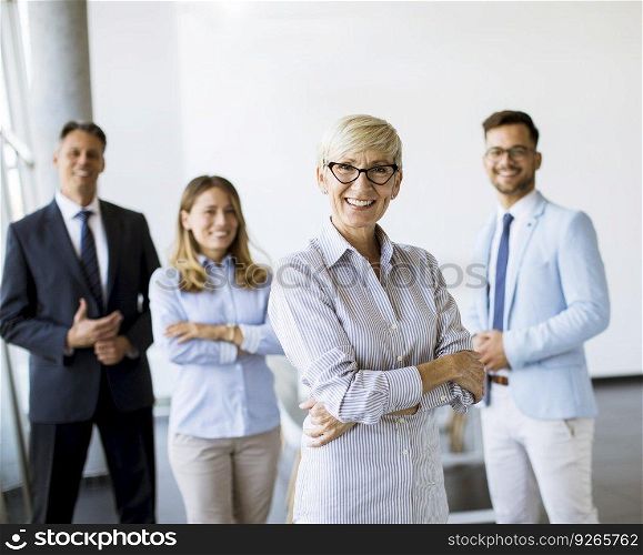 Group of a businesspeople standing together in the office with their mature female bussines leader