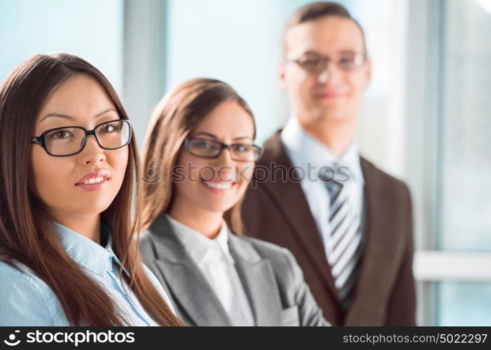 Group of a successful business people standing together at office and smiling