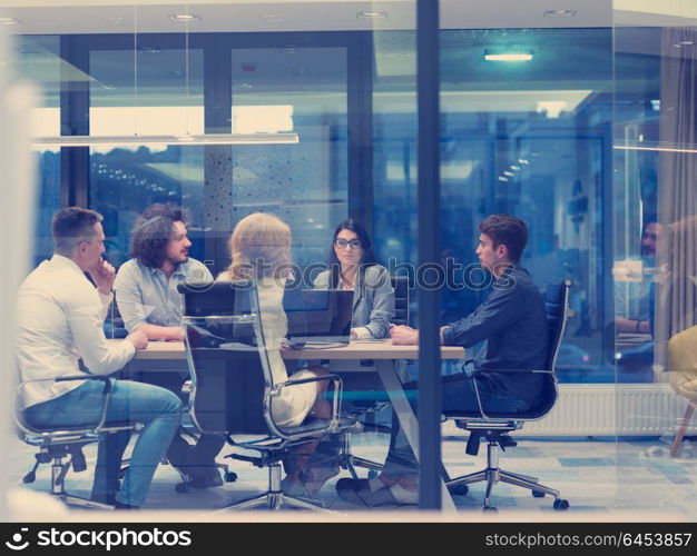 Group of a young business people discussing business plan at modern startup late night office building