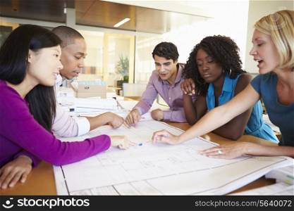 Group Of Architects Discussing Plans In Modern Office