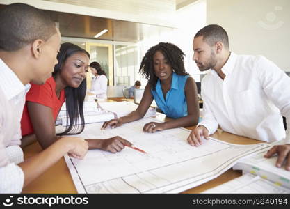 Group Of Architects Discussing Plans In Modern Office