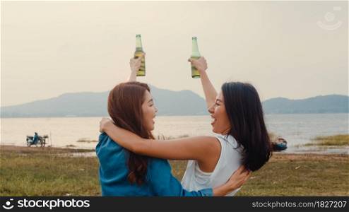 Group of Asia girl couple best friends teenagers drinking have fun salute toast of bottle beer enjoy party with happy moments together in campsite. On background beautiful nature, mountains and lake.