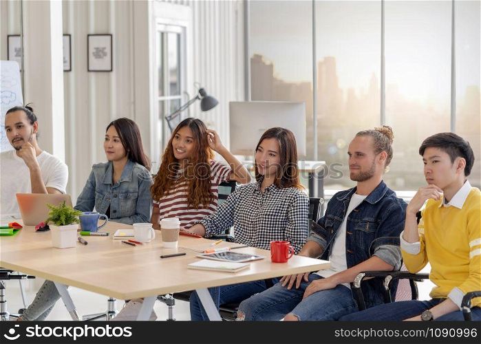 Group of Asian and Multiethnic Business member team with casual suit in listening the senior manager giving the speech in front of the modern workplace, diversity concept