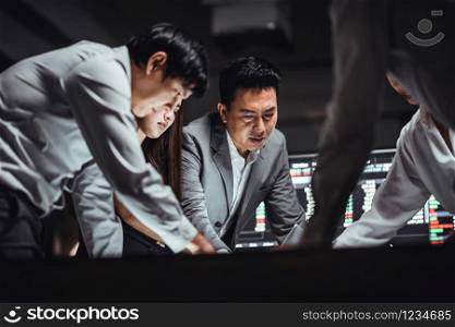 Group of Asian business financial team in strategic meeting, work late night shift in office. Business strategy analysis, stock market trading, or colleague coworker teamwork concept