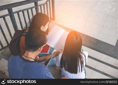 Group of Asian college student using tablet and mobile phone outside classroom. Happiness and Education learning concept. Back to school concept. People theme. Outdoors and Technology theme. Back view