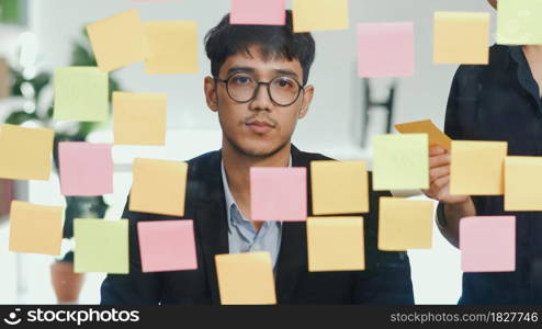 Group of Asian creative men workshop and brainstorm in front of mirror board. Young professional business team working create strategy, business situation, startup in Loft office concept.