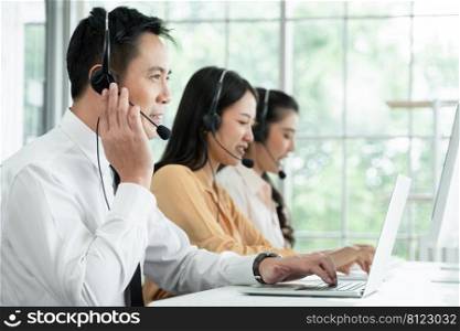 Group of Asian employee work in telemarketing customer service teams. Young operator man working with headset smiling and doing customer support at work. Call Center with service mind concept