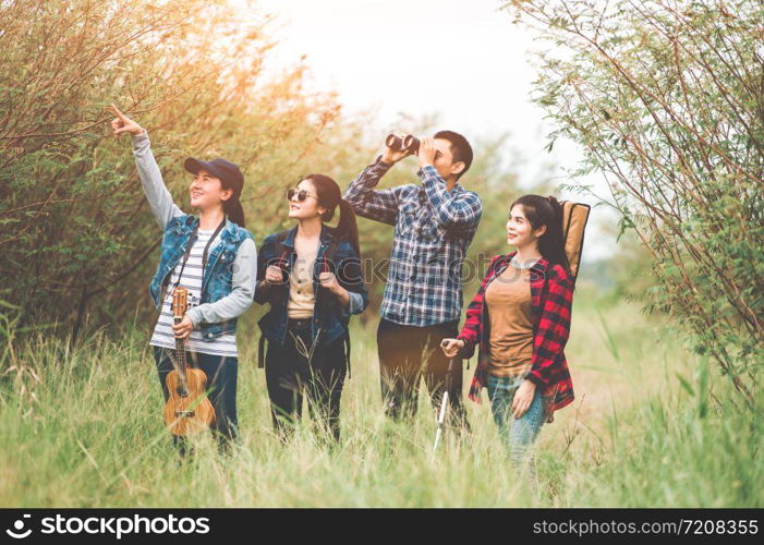 Group of Asian friends team adventure for hiking and camping in forest together. Family travel relaxation. Trekking and trail activity in wild life concept. Woman pointing at tree or sky. Copy space