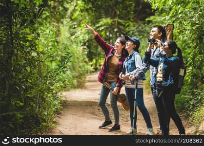 Group of Asian friends team adventure for hiking and camping in forest together. Family travel relaxation. Trekking and trail activity in wild life concept. Woman pointing at tree or sky. Copy space