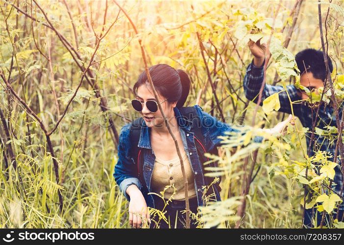 Group of Asian friendship adventure in forest jungle view background. Girl leading tourism team in nature. People lifestyle travel on vacation concept. Summer picnic and camping. Trekking hiking