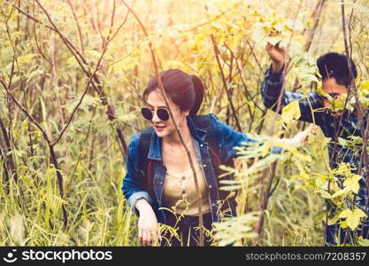 Group of Asian friendship adventure in forest jungle view background. Girl leading tourism team in nature. People lifestyle travel on vacation concept. Summer picnic and camping. Trekking hiking