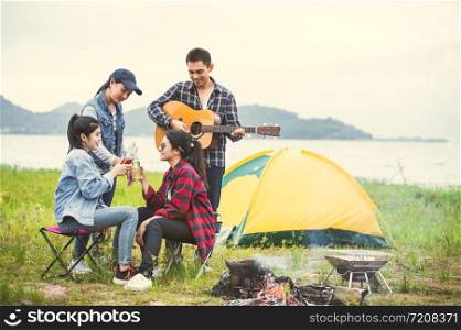 Group of Asian friendship clinking drinking bottle glass for celebrating in private party with mountain and lake view background. People lifestyle travel on vacation concept. Picnic and camping tent
