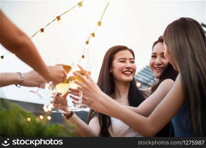 Group of asian multiple gender holding glass of wine chat together with friends while celebrating dance party on outdoor rooftop nightclub,leisure lifestyle of young friendship enjoyment concept.