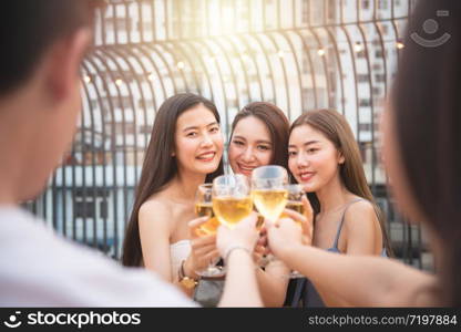 Group of asian multiple gender holding glass of wine chat together with friends while celebrating dance party on outdoor rooftop nightclub,leisure lifestyle of young friendship enjoyment concept.