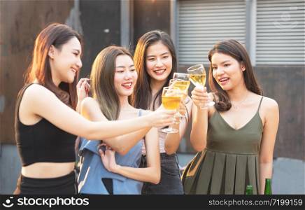 Group of asian multiple gender holding glass of wine chat together with friends while celebrating dance party on outdoor rooftop nightclub,leisure lifestyle of young friendship enjoyment concept.