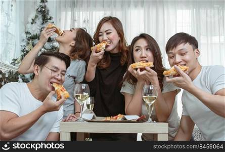 Group of asian people joining party at home, talking and eating pizza together. Lifestyle Concept.