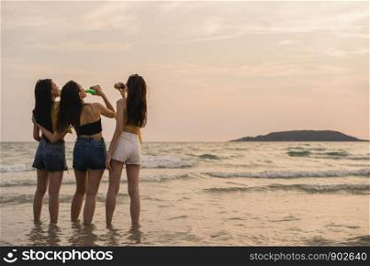 Group of Asian teenage girls having party celebrating on beach, friends happy drinking beer on beach at sea when sunset in evening. Outdoor activity friends travel holiday vacation summer concept.