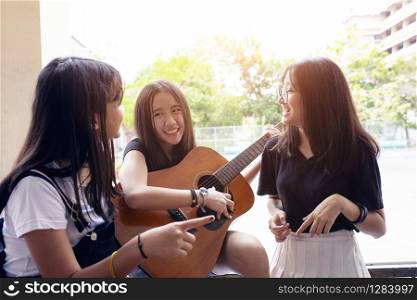 group of asian teenager standing outdoor plying spanish guitar and dancing with happiness emotion