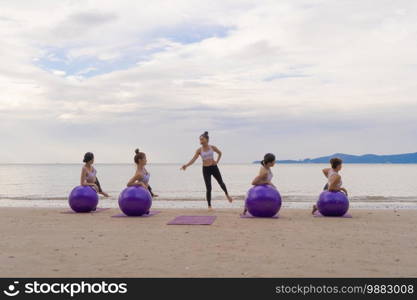 Group of Asian women in yoga class club doing exercise and yoga at natural beach and sea coast outdoor in sport and recreation concept. People lifestyle activity.